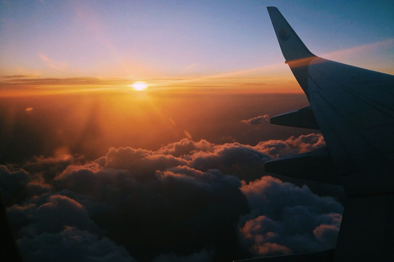 A commercial airliner banking against a dusk sky.