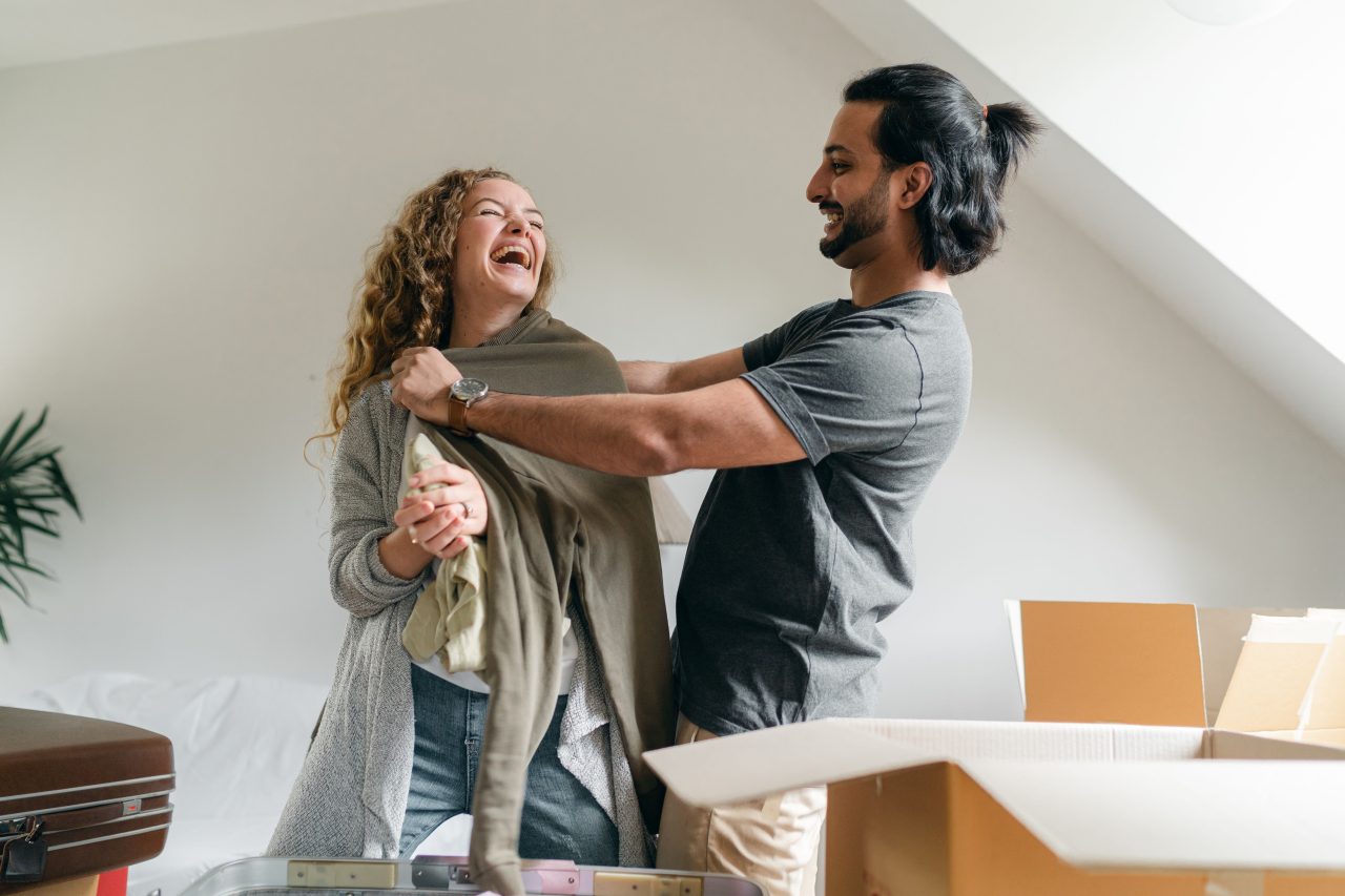 A couple unpacking boxes and laughing together in their new home